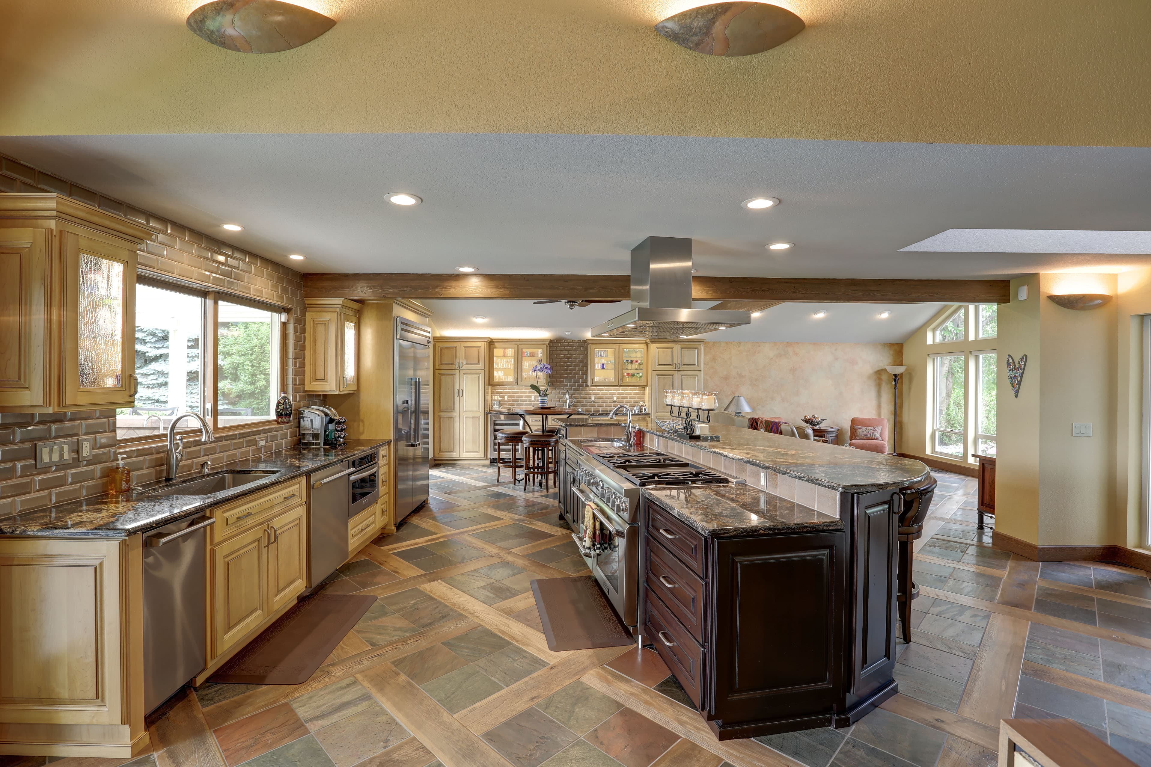 Spacious kitchen featuring light wood cabinets, a dark island, and a unique patterned tile floor.
