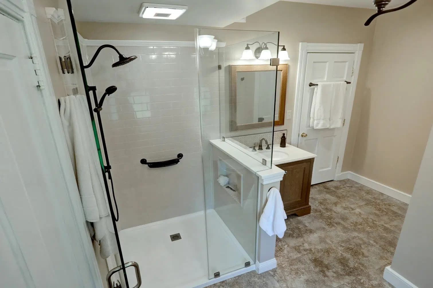 Modern bathroom featuring a glass-enclosed shower with white subway tile and a wood vanity.